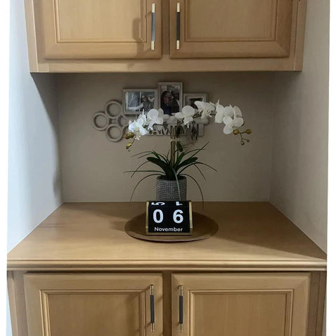 Wooden cupboard with gold and black knurled bar cabinet pulls, displaying a floral arrangement and decorative accents.