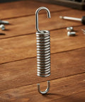 Solid Build 3-5/8 Stainless Steel Recliner Mechanism Tension Spring With Long Neck Hook for furniture repairs on wooden surface.