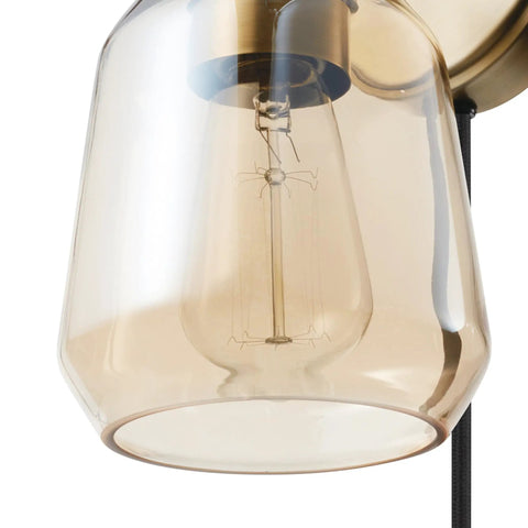 Close-up of smoked amber glass shade on Dope 1 Light Plug In Or Hardwire Wall Sconce In Matte Brass With Black Fabric Cord
