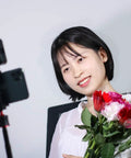 Woman holding flowers illuminated by VL49 2000mAh LED Video Light With 3 Cold Shoe Mounts for vlogging, with soft daylight lighting.