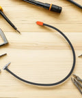 Solid As A Rock Metal High Pressure Tire Inflator Extension Hose Leakproof Design Universal Fitment For Your Car Or Bike To Stay Pressed Up No Drama With Wear Resistance To Handle Any Job Wherever You Are From Garage To Highway. Black metal tire inflator extension hose with orange fitting on wood table, close-up