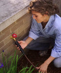 Person connecting Drip Irrigation Faucet Connection Kit for 1/2 Inch Tubing to outdoor garden faucet on red brick wall