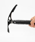 Hand holding Double Headed Folding Pickaxe And Mattock For Camping And Yard Work All Purpose Tool With Garden Hoe And Survival Knife