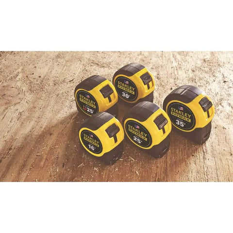 Five yellow and black tape measures of various sizes on wooden surface, indicating a collection of FatMax Tape Measure 1-1/4 Inch By 30 Foot.