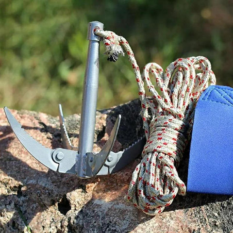 Folding Grappling Hook With 4 Sharp Prongs Aluminum Survival Anchor Tool With 32-Foot Braided Rope And Red Tracking Line on rock