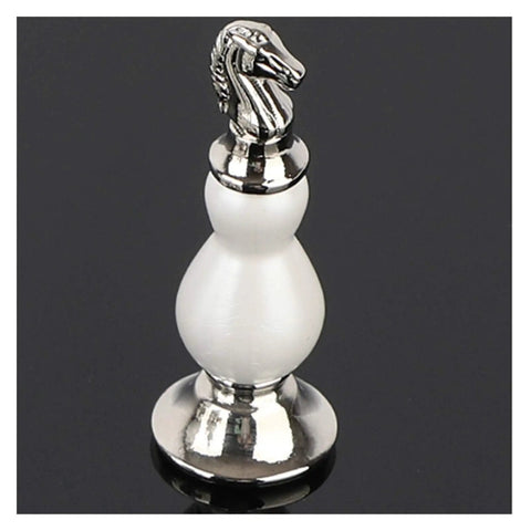 Silver and white metal chess piece with horse head design on black surface