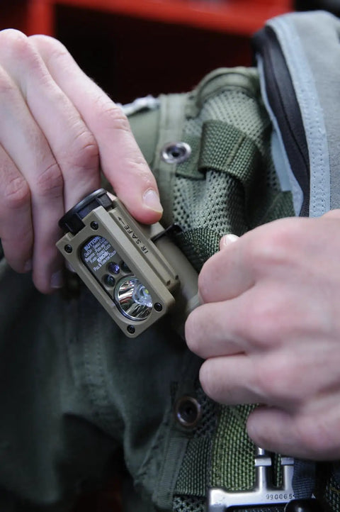 Sidewinder 47 Lumen Compact II Rescue Flashlight With Rail Mount And Headstrap in use on MOLLE gear, showing hands-on attachment.