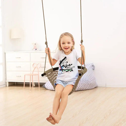 Child on hand knitted toddler swing seat with adjustable ropes, indoor setting, light brown, ergonomic and safe design.