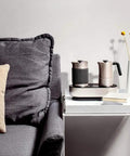 Mini Espresso Maker With Dual Pressure Extraction And Silky Milk Frother Styled Like A Classic Moka Pot on a table beside a sofa.