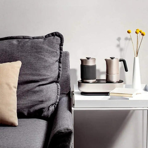 Mini Espresso Maker With Dual Pressure Extraction And Silky Milk Frother Styled Like A Classic Moka Pot on a table beside a sofa.