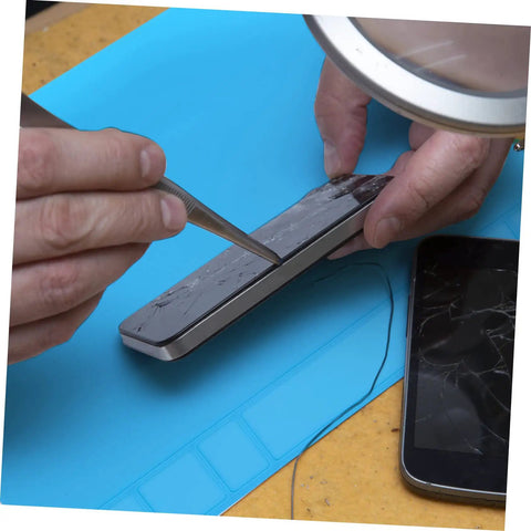 Repairing a cracked smartphone screen on a Heavy Duty Silicone Soldering Mat Heat Resistant Workbench Repair Pad for Phones Tablets PC And Watches.