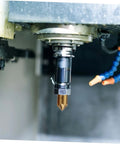 Gold carbide flute chamfer cutter with hex shank installed in a CNC milling spindle; blue coolant hose visible.