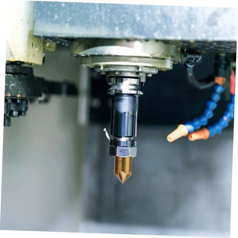 Gold carbide flute chamfer cutter with hex shank installed in a CNC milling spindle; blue coolant hose visible.