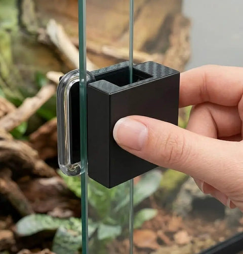 Rock Solid Sliding Door Lock For Reptile Enclosures with secure latch attached to glass tank, showing hand installation.