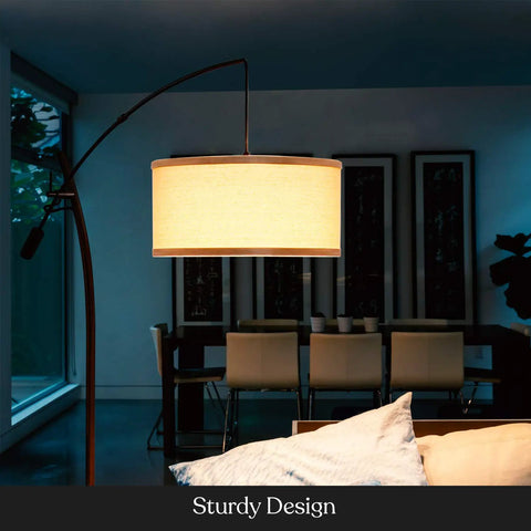Arc Floor Lamp With Linen Shade Sleek Bronze Finish Adjustable Arm For Living Room Office Reading Over Sofa Industrial Style Lighting For Cozy Corners And Nooks, illuminating a living area.