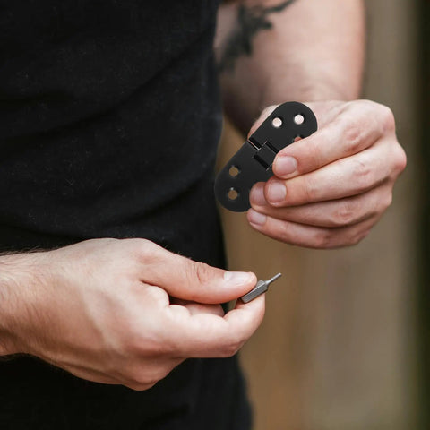 Close-up of a person holding 8 Piece Black Zinc Alloy Folding Table Flip Top Hinges With 180 Degree Round Edge Design.