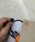 Hand holding KI0207 Capacitive Proximity Sensor Switch For Automation and Robotics Control with visible connector plug