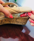 Person applying Clear Shoe Repair Adhesive Mini 0.18 Fl Oz Waterproof Sealant to a worn sole of a wedge sandal for repair.
