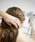 Person using Premium Handheld Shower Head With AnyStream 360° Technology, Adjustable Spray Modes, in contemporary bathroom setting.