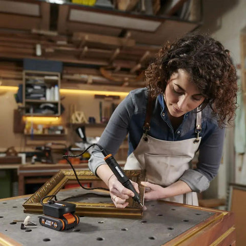 A woman using the Top Tier Cordless Pen Engraver And Digital Soldering Iron Kit With Sweet 20V Battery on a wood frame.