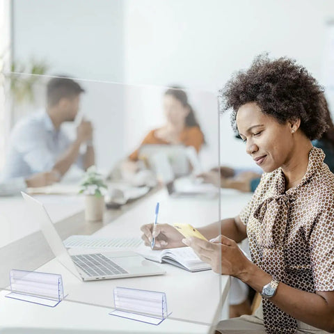 Woman using phone at a desk with Six Pack Heavy Duty Self Adhesive Sneeze Guard Holders for quarter inch acrylic sheets.