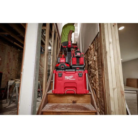 Worker carrying tools on stairs with Six Bay M18 Rapid Charger For Batteries, Dual Charge Two At Once Up To 40 Percent Faster Than Standard.