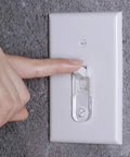Person using Clear Toggle Switch Plate Guard from 10 Pack for Indoor and Outdoor Wall Plates on a standard wall switch.