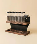 Heavy Hitter Coffee Bean Storage Rack With Twelve Clear Glass Bottles And Solid Wood Base in a modern design with a funnel.