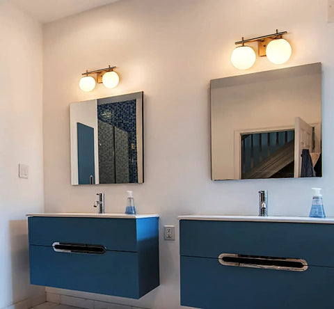Gold Two Light Wall Sconce With Brass Finish And Milky White Glass Globe above bathroom mirrors in contemporary setting.
