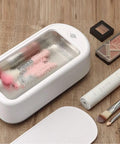 All In One Ultrasonic Glasses And Jewelry Cleaner 640ML 48KHz Powerful Sonic Cleaning Machine For Rings Gold Silver Eyeglasses And Dental Care Home Use on wooden surface with makeup brushes.