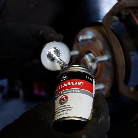 Mechanic applying Premium 4oz Brush Top SIL Glyde Silicone Brake Grease for Calipers and Brake Lubrication by AGS Automotive Solutions