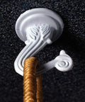Jumbo Swag Hook With Hardware White Enamel mounted on wall holding rope, features ornate white design with easy installation hardware