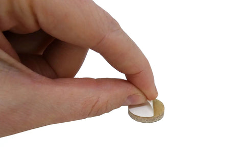Hand peeling backing from Self Adhesive Felt Furniture Pads 3/4 Inch Beige 120 Pack, Scratch Free Glide For Hardwood Tile And Laminate Floors.