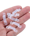 Close-up of hand holding half-milk colored clips from 100 Pack LED Strip Light Mounting Brackets And Clips With Holders And 200 Screws