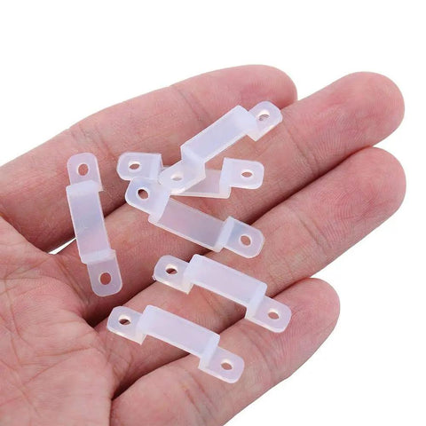 Close-up of hand holding half-milk colored clips from 100 Pack LED Strip Light Mounting Brackets And Clips With Holders And 200 Screws