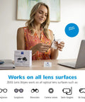ZEISS Pre-Moistened Lens Cleaning Wipes, 200-count box on desk; person holding glasses