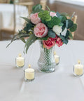 Eight-Hour Smokeless Dripless Ivory Votive Candles Bulk Pack Of 72 Sticks, displayed around flower vase on table