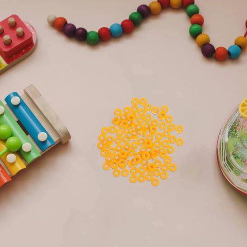 100 Pack Miniature Plastic Bushings and Axle Sleeves for Toy Vehicles surrounded by colorful toys on a table.