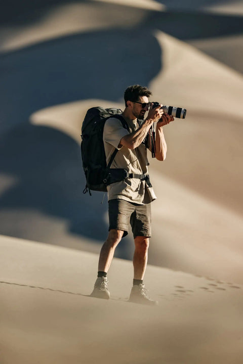 Photographer with 80L Adventure Camera Backpack For DSLR And Cinematography Gear With Cine Master ICU in desert landscape