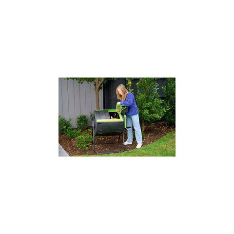 Person using the 48 Gallon Dual Compartment Compost Tumbler with No-Fuss Turn and Continuous Cycle in a garden setting.