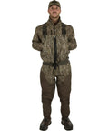 Model wearing Men's Insulated Guardian Elite Front Zip Wader with TiZIP MasterSeal 10 and boots in Mossy Oak Bottomland