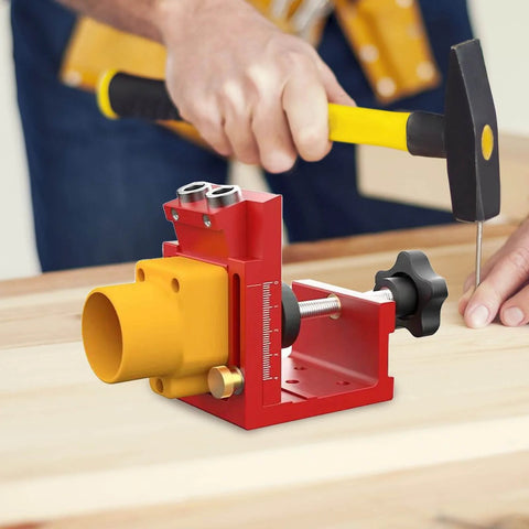 Red pocket hole drill jig with dust collection for cabinet installation, deck building, and desk assembly in use on wood surface.