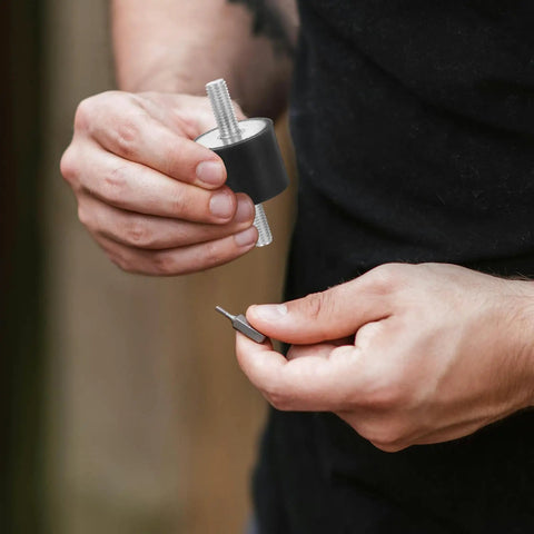 Person holding Four Piece Built For The Grind Anti Vibration Rubber Studs M10 Double Screw Mount with tool.