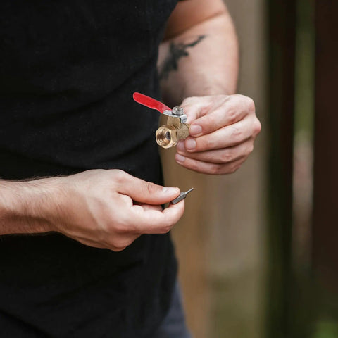 Person holding Tough As Nails Four Inch Mini Ball Valve With Slick Lever Handle and threaded end for plumbing use.