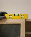 Spirit Level, Aluminum Alloy, 250mm on a cabinet, held with gloved hand for precise leveling.