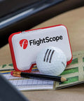 Mevo Portable Golf Launch Monitor And Rangefinder With Signature Gift Bundle featuring monitor, golf ball, and pencil on scorecard