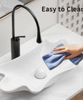 HAOCHRYSYPH Ceramic Shell Vessel Sink Bowl, Milk White, 24.41x13x4.73 in. being cleaned with a cloth, showcasing its smooth surface.