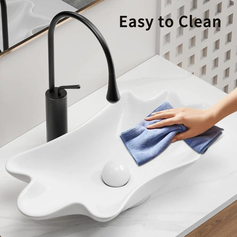 HAOCHRYSYPH Ceramic Shell Vessel Sink Bowl, Milk White, 24.41x13x4.73 in. being cleaned with a cloth, showcasing its smooth surface.