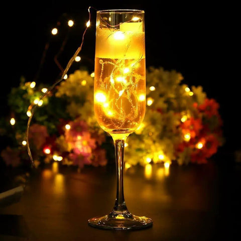 Warm White Battery Operated Fairy String Lights 10 Ft Copper Wire Set in a champagne glass with glowing effect