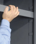 Hand placing an adjustable shelf in a Heavy Duty Steel Garage Cabinet With Three Adjustable Shelves And 72 Bright Yellow Parts Bins.